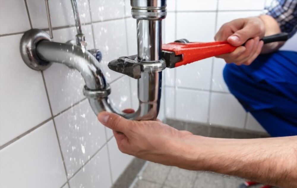 plumbing wrench being used by a plumber to stop a leak